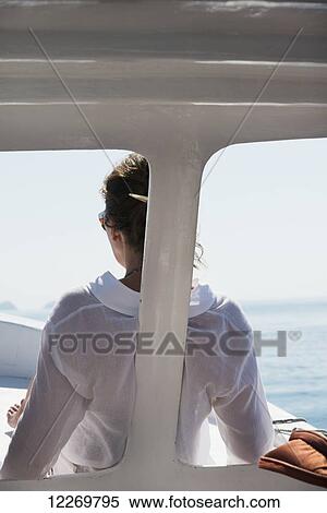 Stock Photography - A woman in a white shirt sits at the front of a boat with a view of the ocean; Ixtapa-Zihuatanejo, Guerrero, Mexico. Fotosearch