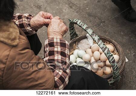 Stock Image - A woman selling chicken eggs in Bashi, eighth market, a traditional Chinese market where we can find all different kinds of food; Xiamen, Fujian Province, China. Fotosearch