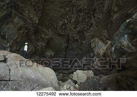 Stock Image - A woman standing at the entrance to a large cave in Toro Toro National Park; Bolivia. Fotosearch