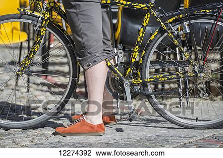 A woman wearing orange shoes standing with her bicycle; Locarno, Ticino, Switzerland View Large Photo Image Stock Image - A woman wearing orange shoes standing with her bicycle; Locarno, Ticino, Switzerland. Fotosearch