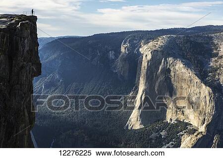 Stock Photography - A Yosemite National Park visitor stands at Taft Point, which overlooks Yosemite Valley and El Capitan; California, United States of America. Fotosearch