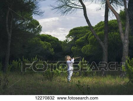 Stock Image - A young boy looks through a telescope standing in the grass; Tarifa, Cadiz, Andalusia, Spain. Fotosearch