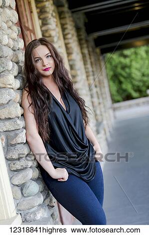 A young female millennial in a fashionable outfit hangs out casually outside of a restaurant leaning into the wall; Vancouver, British Columbia, Canada View Large Photo Image Stock Photograph - A young female millennial in a fashionable outfit hangs out casually outside of a restaurant leaning into the wall; Vancouver, British Columbia, Canada. Fotosearch