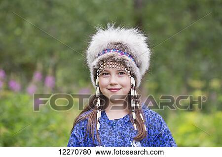 Stock Image - A young Inupiat tween girl in a traditional Eskimo Kuspuk and native headdress, Hatcher Pass, Palmer, Southcentral, Summer. Fotosearch