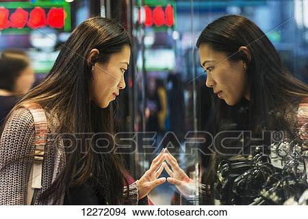 A young woman and her reflection in the glass peering into a shop window, Kowloon; Hong Kong, China View Large Photo Image Picture - A young woman and her reflection in the glass peering into a shop window, Kowloon; Hong Kong, China. Fotosearch