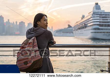 A young woman at the waterfront with cruise ships in the harbour in the background, Kowloon; Hong Kong, China View Large Photo Image Stock Image - A young woman at the waterfront with cruise ships in the harbour in the background, Kowloon; Hong Kong, China. Fotosearch