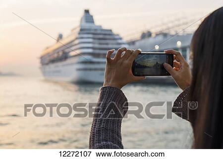 A young woman photographs a cruise ship in the harbour at sunset, Kowloon; Hong Kong, China View Large Photo Image Stock Photo - A young woman photographs a cruise ship in the harbour at sunset, Kowloon; Hong Kong, China. Fotosearch