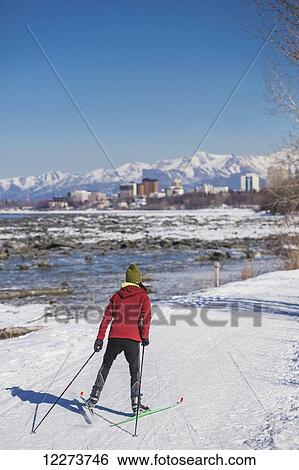 Stock Photograph - A young woman skate skiing down the Tony Knowles Coastal Trail, Anchorage, Southcentral Alaska, USA.. Fotosearch