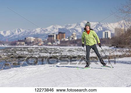 Stock Photograph - A young woman skate skiing down the Tony Knowles Coastal Trail, Anchorage, Southcentral Alaska, USA.. Fotosearch