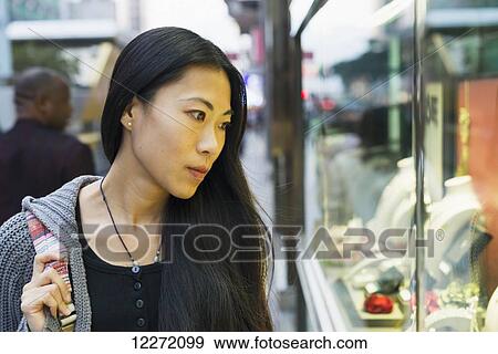 Stock Photo - A young woman window shopping at the retail shops along the street, Kowloon; Hong Kong, China. Fotosearch