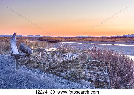 Stock Photo - Abandoned wooden mushing sleds and a Bowhead Whale jaw bone along the bank of the Noatak River during Sunset, Noatak, Arctic Alaska, USA, Fall, HDR Image. Fotosearch
