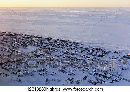Stock Photograph - Aerial sunrise view of the village of Nome on the Seward Peninsula and the frozen Bering Sea; Nome, Alaska, United States of America. Fotosearch