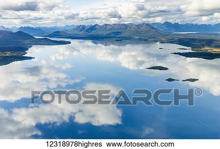 Stock Photograph - Aerial view of clouds reflecting on the glassy surface of Nerka Lake, the Wood River Mountains in the background, Wood Tikchik State Park, Southwestern Alaska; Alaska, United States of America. Fotosearch