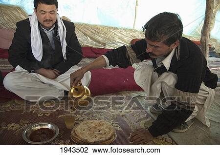 Stock Image - Afghan Man Pouring Tea At A Larger Chaikhana Located By The Side Of The Kabul To Sarobi Road, Kabul Province, Afghanistan. Fotosearch
