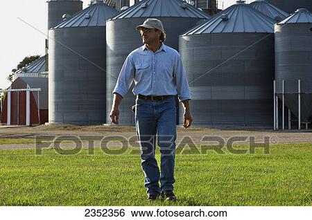 Agriculture - A farmer walks across his farm View Large Photo Image Stock Photograph - Agriculture - A farmer walks across his farm. Fotosearch