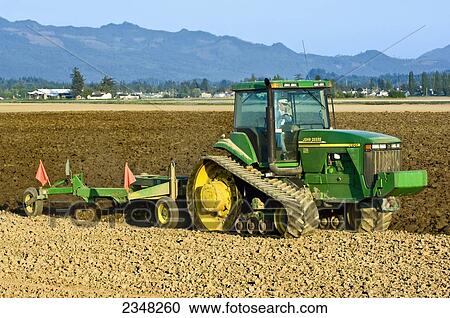 Agriculture - A John Deere tracked tractor pulling a reversible plow prepares a field for planting potatoes / near Burlington, Washington, USA. View Large Photo Image Stock Image - Agriculture - A John Deere tracked tractor pulling a reversible plow prepares a field for planting potatoes / near Burlington, Washington, USA.. Fotosearch