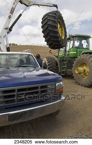 Stock Photography - Agriculture - A tire technician works to change a tractor tire in the field during planting season / near Pullman, Palouse Region, Washington, USA.. Fotosearch