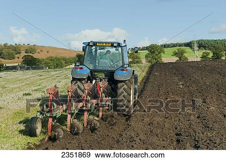 Agriculture - A tractor with a 4-furrow reversible plow preparing a field for planting / England, United Kingdom. View Large Photo Image Stock Photo - Agriculture - A tractor with a 4-furrow reversible plow preparing a field for planting / England, United Kingdom.. Fotosearch