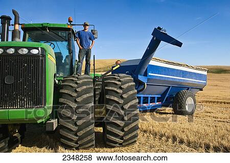 Agriculture - A young farmer atop his tractor during a short break from harvest in the Palouse region / near Pullman, Washington, USA. View Large Photo Image Stock Photo - Agriculture - A young farmer atop his tractor during a short break from harvest in the Palouse region / near Pullman, Washington, USA.. Fotosearch