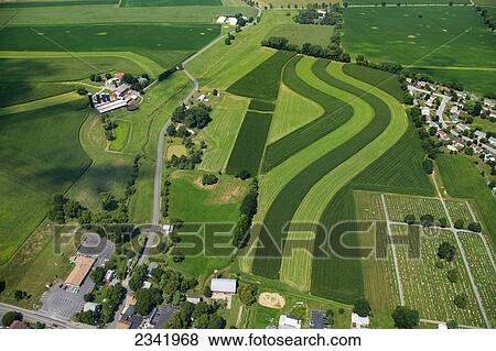 Agriculture - Aerial view of farmsteads and fields utilizing strip cropping, with a cemetery, housing tracts and other buildings and parking lots encroaching on the agricultural land / Pennsylvania, USA. View Large Photo Image Stock Photo - Agriculture - Aerial view of farmsteads and fields utilizing strip cropping, with a cemetery, housing tracts and other buildings and parking lots encroaching on the agricultural land / Pennsylvania, USA.. Fotosearch