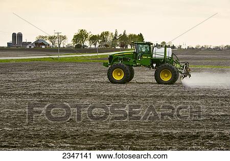 Stock Image - Agriculture - Applying pre-emergent herbicide with a John Deere 4720 sprayer to a newly planted soybean field with the purpose of decreasing weed pressure while optimizing yield potential / Central Iowa, USA.. Fotosearch