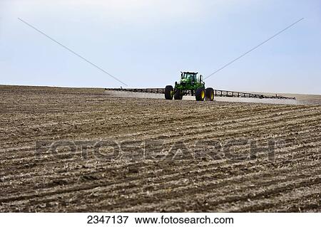 Stock Photo - Agriculture - Applying pre-emergent herbicide with a John Deere 4720 sprayer to a newly planted soybean field with the purpose of decreasing weed pressure while optimizing yield potential / Central Iowa, USA.. Fotosearch