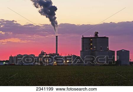 Stock Photo - Agriculture - Ethanol production plant at sunrise with steam rising out of the thermal oxidizer stack and a harvested corn field in the foreground / Iowa, USA.. Fotosearch