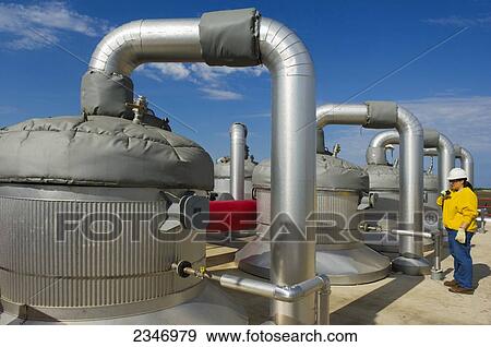 Stock Photo - Agriculture - Ethanol production plant. Technician inspecting cooking units / Iowa, USA.. Fotosearch