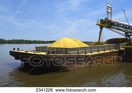 Stock Photograph - Agriculture - Ethanol production plant. Ground corn being loaded onto a barge on the Mississippi River after it has been used for ethanol production.. Fotosearch
