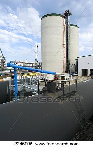 Stock Photography - Agriculture - Ethanol production plant. Railroad tank cars being bulk loaded with ethanol in the foreground. Grain silos in background / Iowa, USA.. Fotosearch