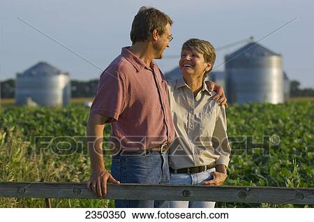 Agriculture - Husband and wife farmers in their mid growth soybean field share some personal moments together, with grain bins in the background / Minnesota, USA. View Large Photo Image Stock Image - Agriculture - Husband and wife farmers in their mid growth soybean field share some personal moments together, with grain bins in the background / Minnesota, USA.. Fotosearch