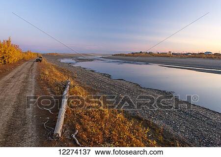 Stock Photo - An ATV sits on the banks of the Noatak River with colorful tundra and golden willows lining the River, Noatak, Arctic Alaska, USA, Fall. Fotosearch