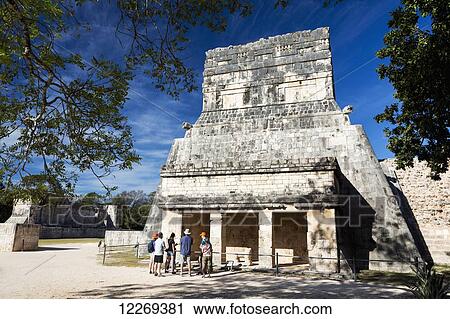 Ancient Mayan Temple framed by trees with tourist on tour and blue sky; Chichen Itza, Yucatan, Mexico View Large Photo Image Stock Image - Ancient Mayan Temple framed by trees with tourist on tour and blue sky; Chichen Itza, Yucatan, Mexico. Fotosearch