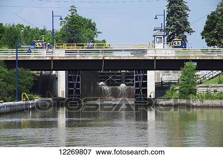 Stock Photo - Approaching lock 33 near Pittsford, doors open, water leaking in from upstream; New York, United States of America. Fotosearch