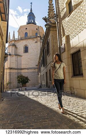 Stock Photograph - Asian girl walking along the street with Segovia's Cathedral as background; Castilla Leon, Spain. Fotosearch