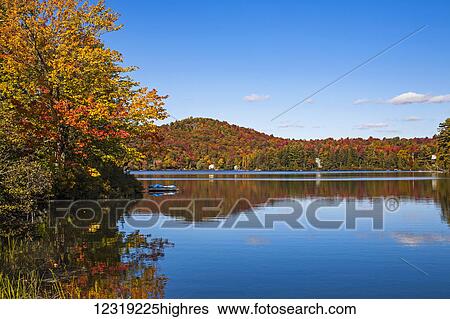 Stock Photograph - Autumn coloured trees around a lake; Sugarloaf Pond, Quebec, Canada. Fotosearch