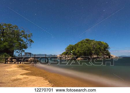 Stock Image - Beach and small bridge going from Mumbo Island to small island for tourist's accommodation under a starry sky, Lake Malawi; Malawi. Fotosearch