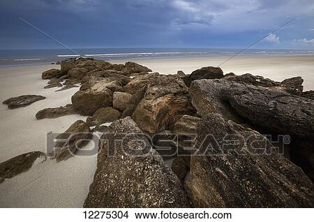 Beach in Northeast Florida with large rocks trailing down to the surf and stormy clouds in the sky; Florida, United States of America View Large Photo Image Picture - Beach in Northeast Florida with large rocks trailing down to the surf and stormy clouds in the sky; Florida, United States of America. Fotosearch