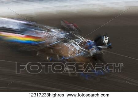 Stock Photograph - Blur of colour and motion of a chuckwagon race, Lakeview Calgary Stampede Event; Calgary, Alberta, Canada. Fotosearch