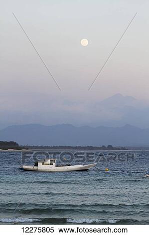 Stock Photography - Boat in the Lombok Strait with Lombok island in the background during full moon, Gili Trawangan, West Nusa Tenggara, Indonesia. Fotosearch