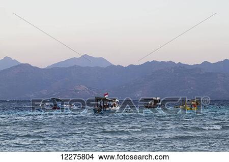 Picture - Boats in the Lombok Strait with Lombok island in the background, Gili Trawangan, West Nusa Tenggara, Indonesia. Fotosearch