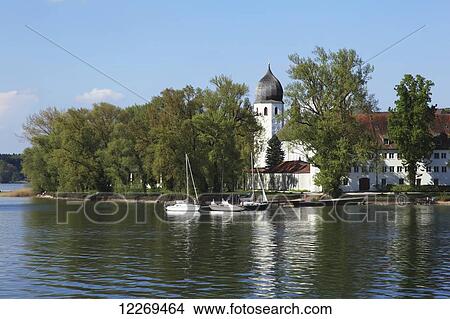Boats moored in a tranquil lake at the water's edge; Die Fraueninsel, Bayern, Germany View Large Photo Image Picture - Boats moored in a tranquil lake at the water's edge; Die Fraueninsel, Bayern, Germany. Fotosearch