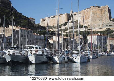 Stock Image - Boats moored in foreground with dramatic fortress walls behind; Bonifacio, Corse-du-Sud, Corsica, France. Fotosearch