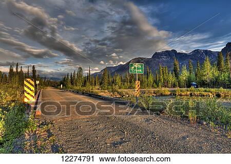 Stock Image - Bridge over Jack Creek on the Nabesna Road with Skookum Volcano at sunset in Wrangell St. Elias National Park and Preserve, Southcentral Alaska, Summer, HDR. Fotosearch