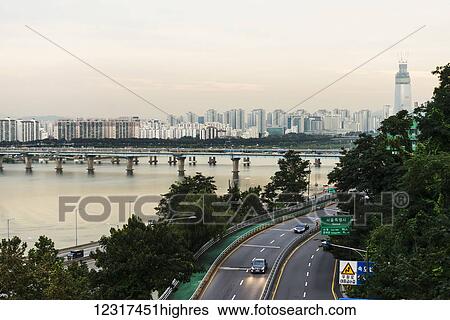 Stock Photograph - Bridges crossing the Han River and a road with buildings in a cityscape; Seoul, South Korea. Fotosearch