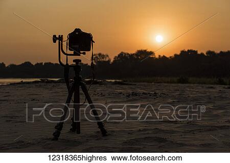 Stock Photograph - Camera on tripod beside river at sunset; Mato Grosso do Sul, Brazil. Fotosearch