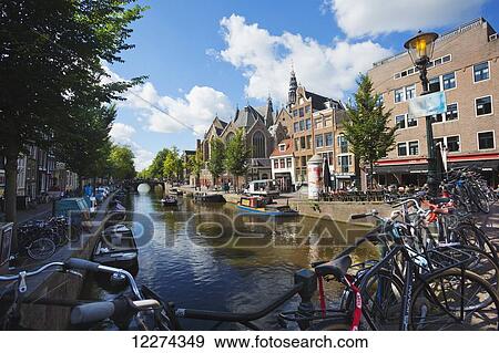 Stock Photo - Canal in Amsterdam with the Old Church in the background on the right; Holland, Amsterdam. Fotosearch