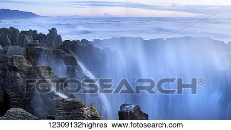 Stock Photograph - Cascading water falling in the Punakaiki blowhole; Punakaiki, South Island, New Zealand. Fotosearch