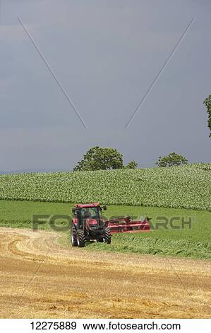 Stock Photo - Case IH Tractor with DC132 Disc Mower cutting Alfalfa; Strasburg, Pennsylvania, United States of America. Fotosearch