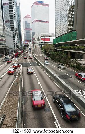 Stock Photo - Central district in Hong Kong Island with red taxis in traffic; Hong Kong, China. Fotosearch